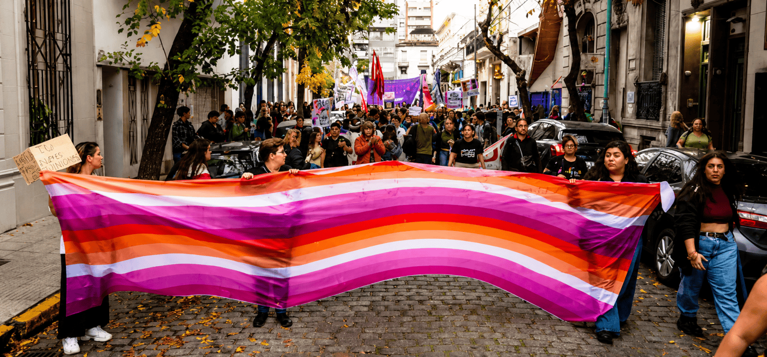 Manifestación en Buenos Aires para pedir justicia por el crimen de Barracas, con activistas sosteniendo una gran bandera lésbica.