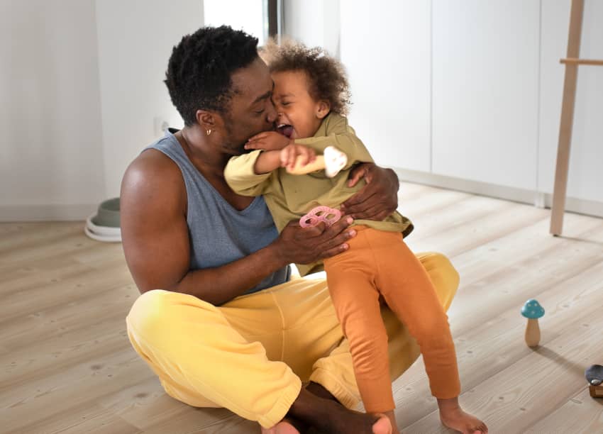 Padre abrazando a su hija en un hogar, representación del derecho humano a un nivel de vida adecuado y a vivir con dignidad y seguridad.