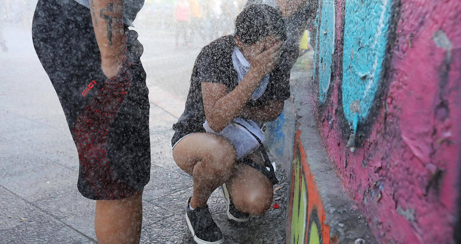 Los manifestantes son rociados por la policía antidisturbios con un cañón de agua durante una protesta convocada por estudiantes de secundaria...