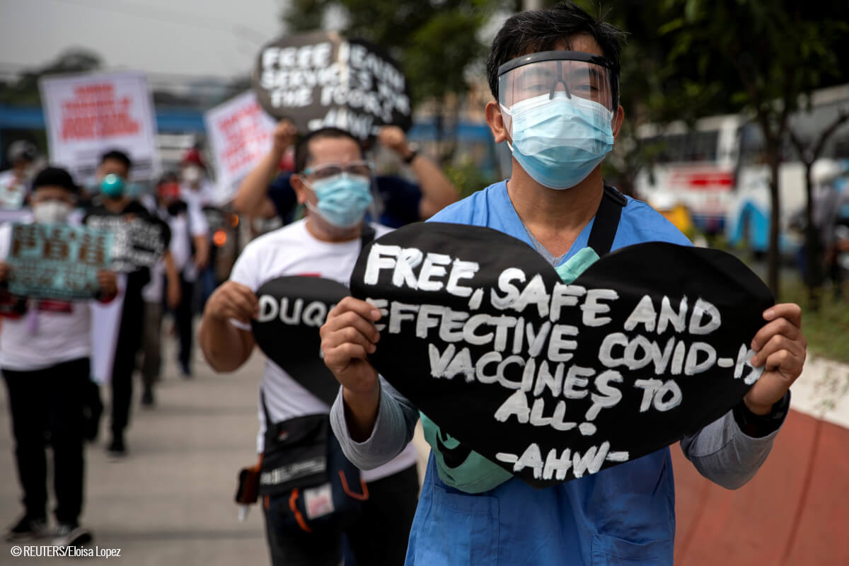 Un trabajador de la salud sostiene un cartel que pide vacunas COVID-19 gratuitas, seguras y efectivas