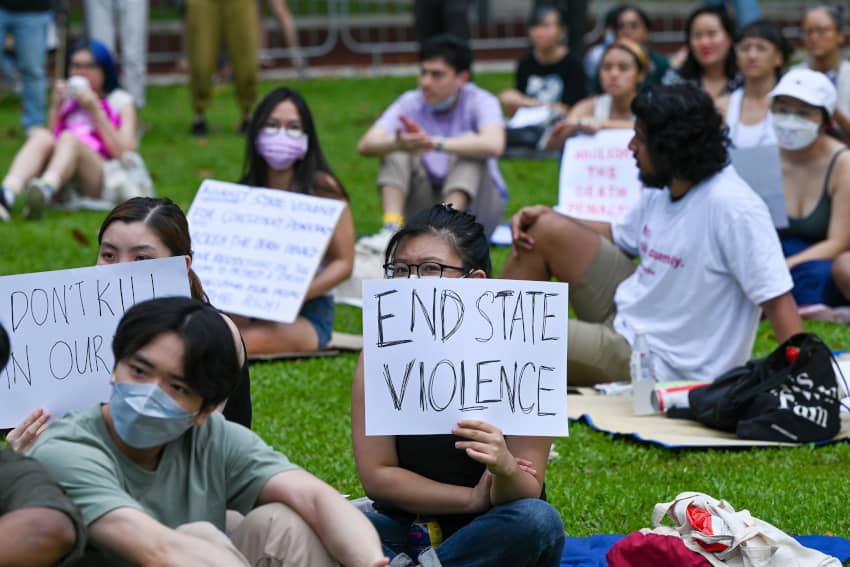 Protesta en Singapur con participantes sosteniendo carteles contra la pena de muerte y la violencia de Estado.