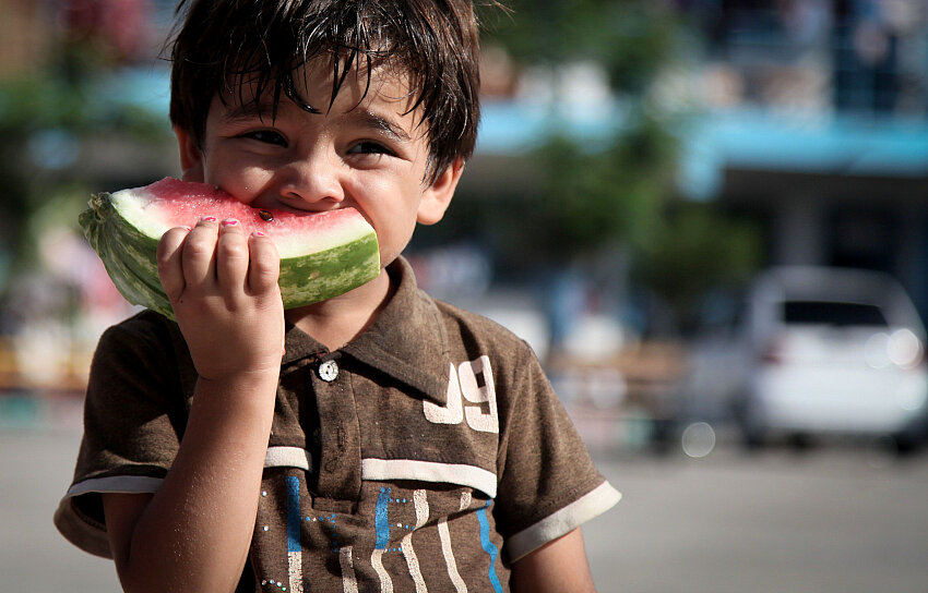 Niño palestino comiendo sandía en una escuela de la ONU en Gaza, símbolo de resistencia y refugio durante el conflicto.