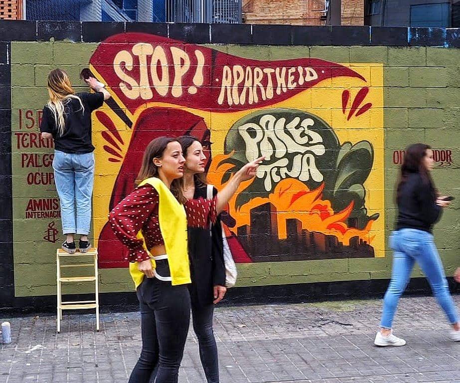 Dos activistas delante de un mural reivindicativo