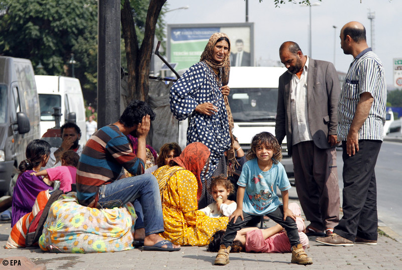Familias refugiadas que huyeron de Siria se sientan en una calle fuera de un parque público en Estambul, Turquía