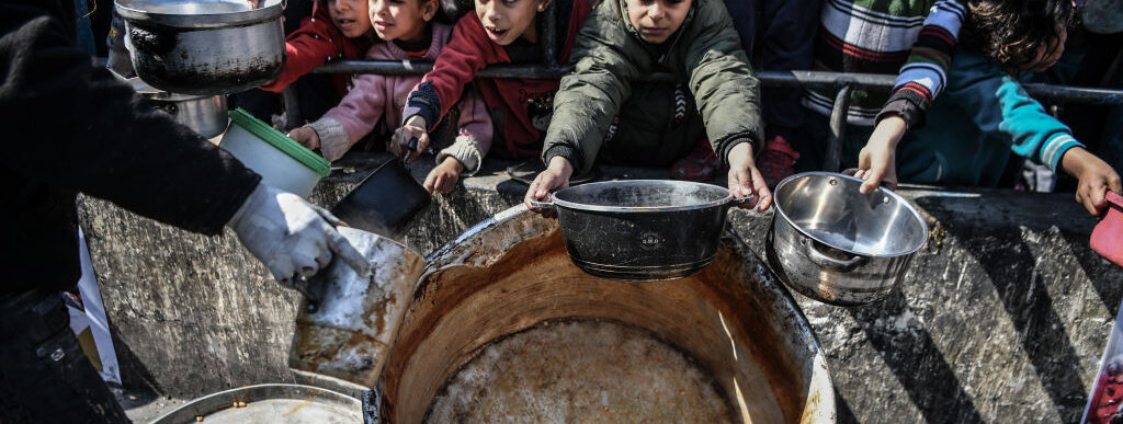 Niños intentando recoger comida en un reparto realizado por organismos internacionales