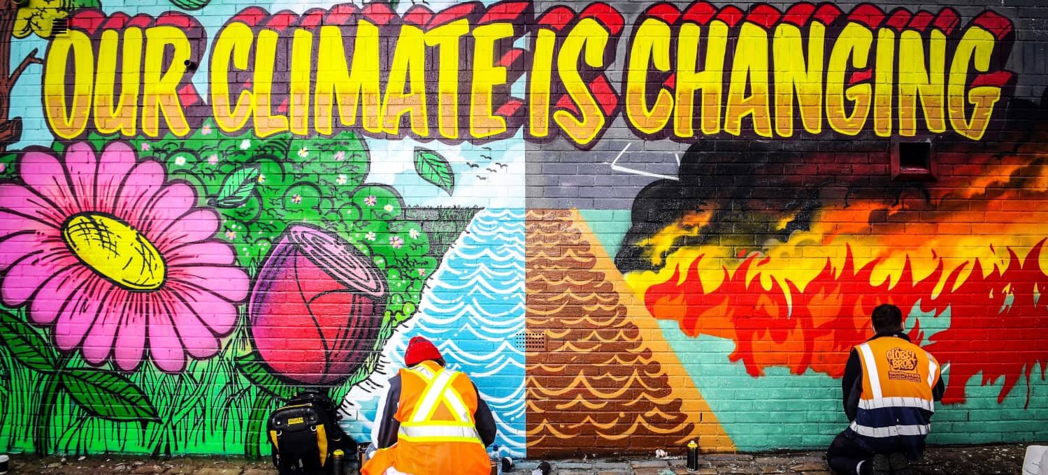 Los artistas callejeros Ciaran Globel y Conzo Throb pintan un mural que es un llamamientos a la acción sobre el cambio climático.Amnistía...
