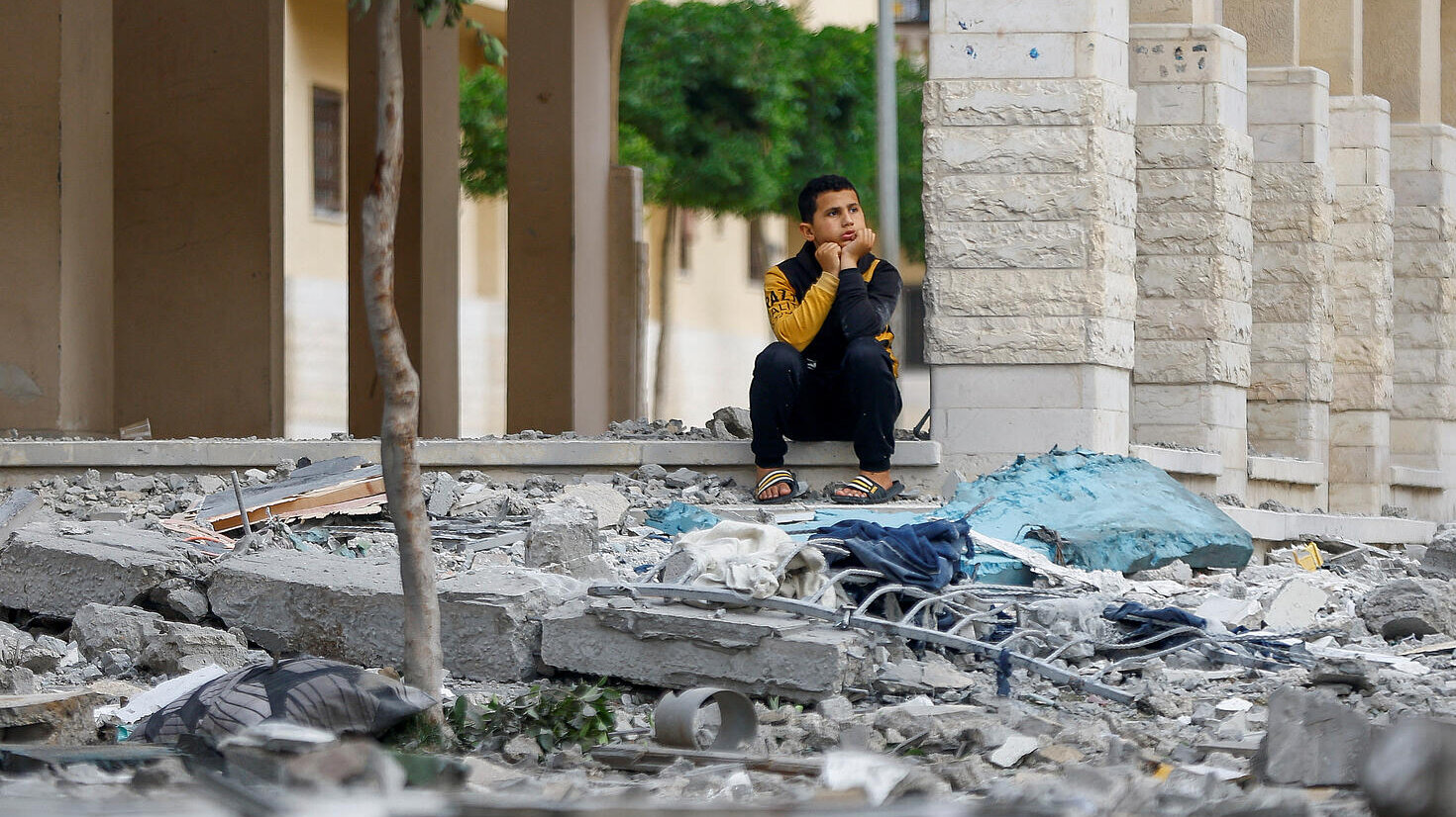 Un niño sentado entre escombros tras ataques israelíes