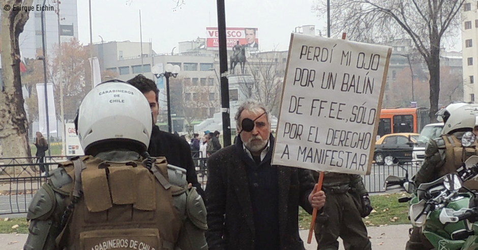 Enrique Eichin con una pancarta contando su caso, delante de carabineros