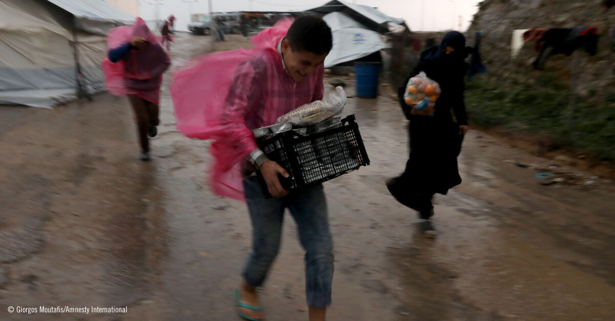 Personas refugiadas llevando comida bajo la lluvia