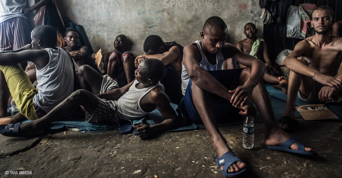 Varios hombres refugiados sentados en el suelo