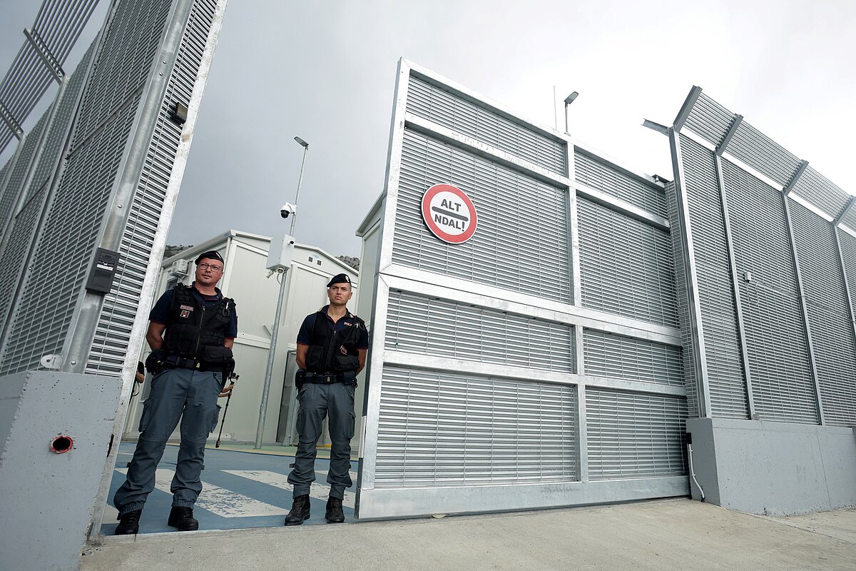 Agentes de policía italianos se encuentran a la entrada de un centro para migrantes de reciente construcción gestionado por Italia en el puerto de...
