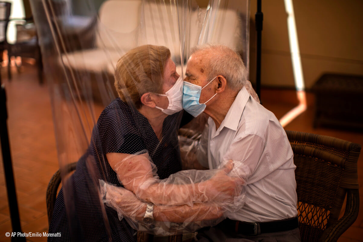 Una pareja de amyores se besa a través de una lámina de plastico