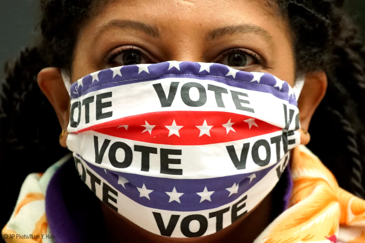 Mujer con mascarilla con el lema: VOTA