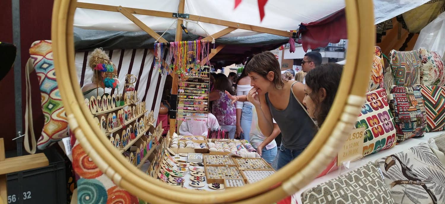 Camino Baró observa artesanías y complementos en un mercado local, reflejo de su vida cotidiana y su activismo por la diversidad corporal.