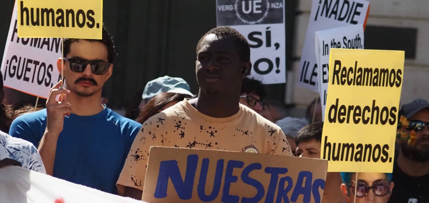 Manifestación antirracista en Madrid con carteles que reclaman derechos humanos para las personas migrantes.