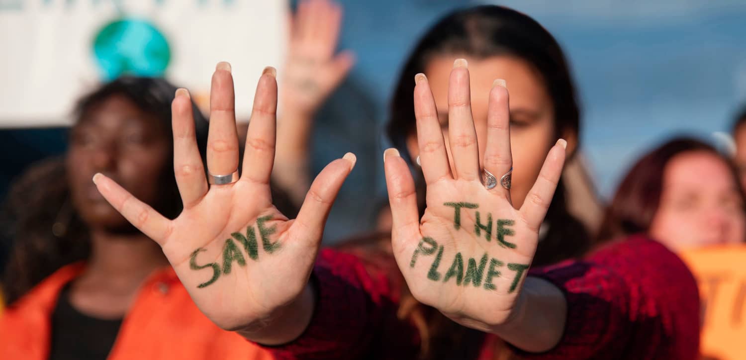 Adolescente mostrando las manos con el mensaje "Save the Planet" durante una actividad de sensibilización ambiental.