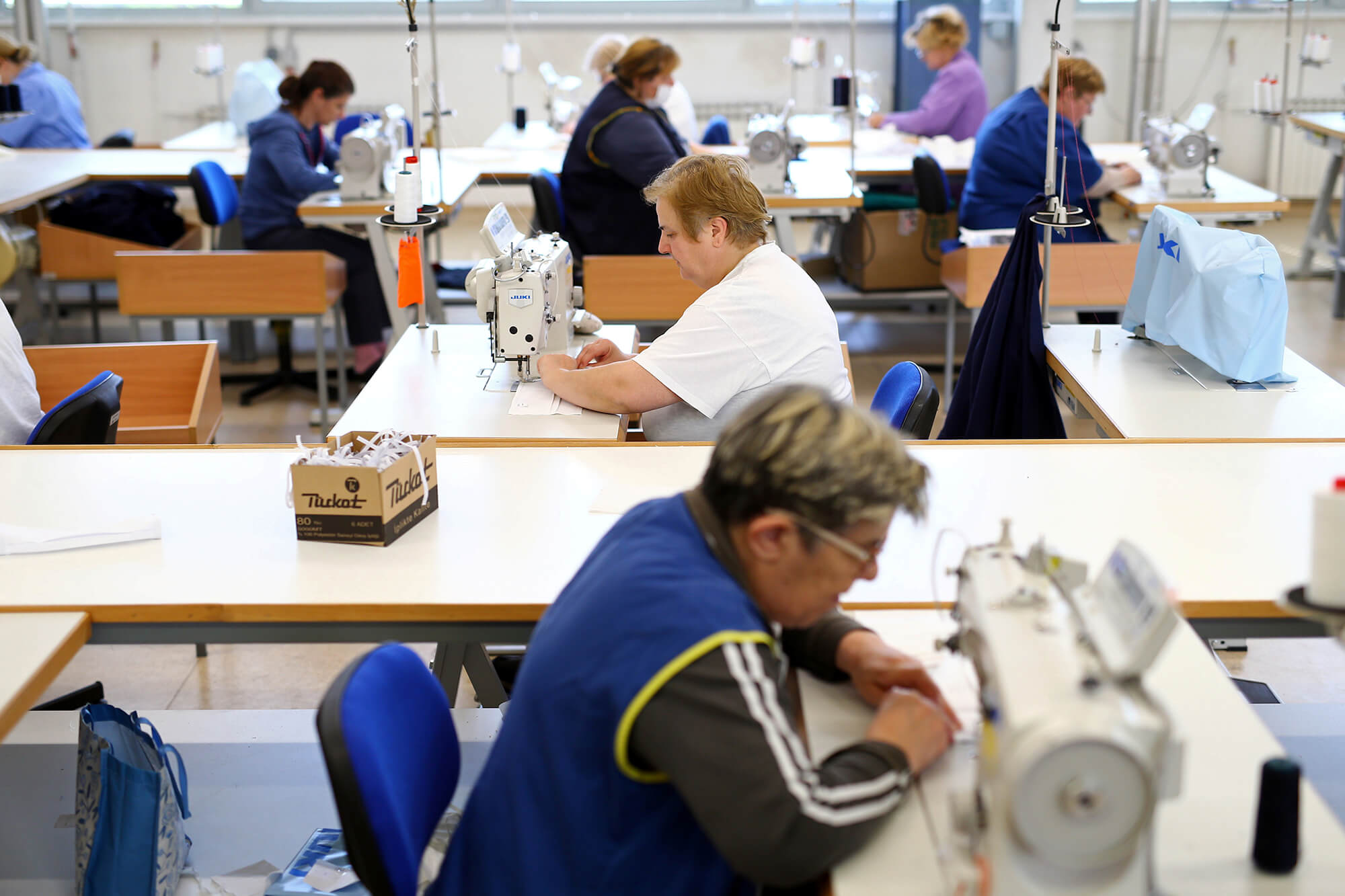 Trabajadores y trabajadoras cosen mascarillas faciales protectoras mientras se intensifican las medidas para combatir el brote de coronavirus...