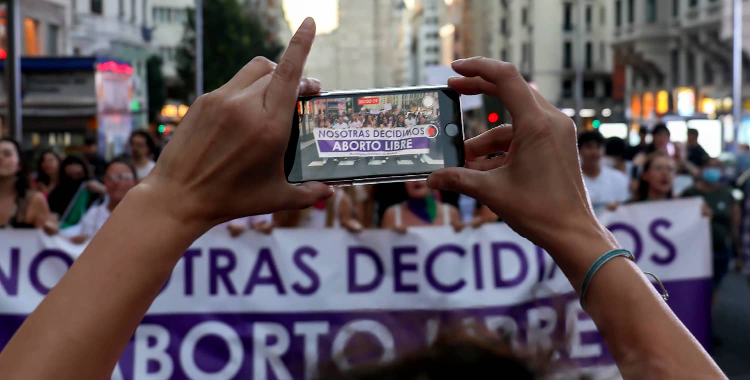 Una mujer graba con su móvil una manifestación feminista por la despenalización del aborto en el centro de Madrid