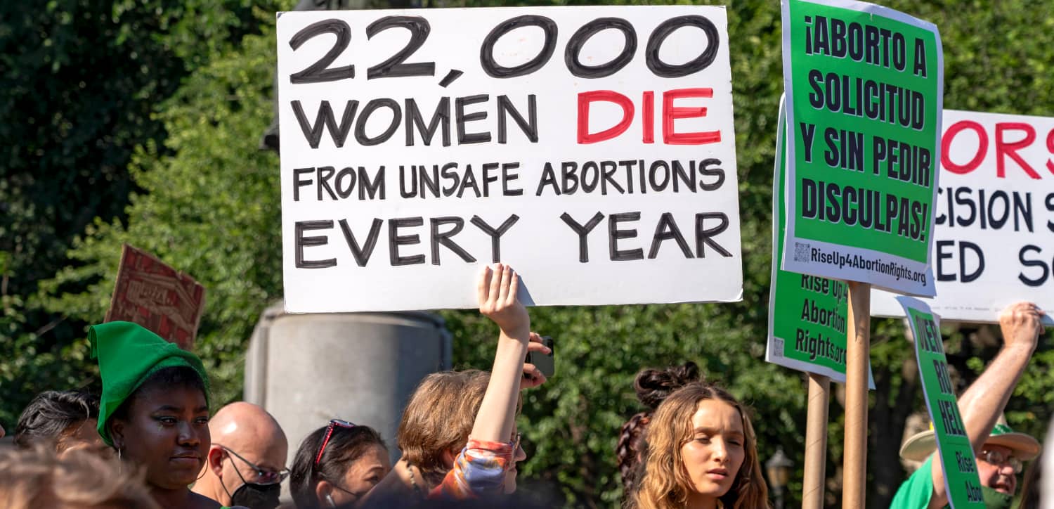 Una mujer sostiene un cartel que dice "22.000 mujeres mueren cada año por abortos inseguros"