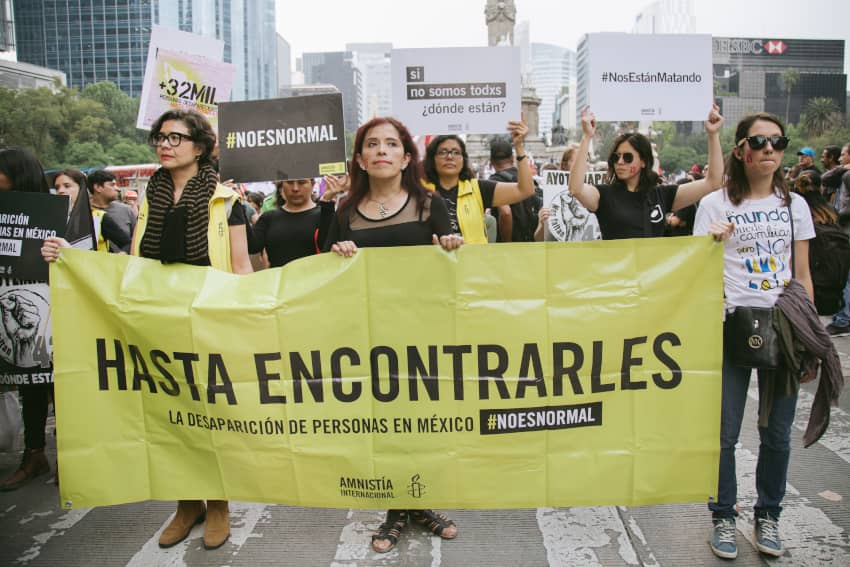 Personas marchan en Ciudad de México con una gran pancarta amarilla de Amnistía Internacional que dice “Hasta encontrarles”, en protesta por la...