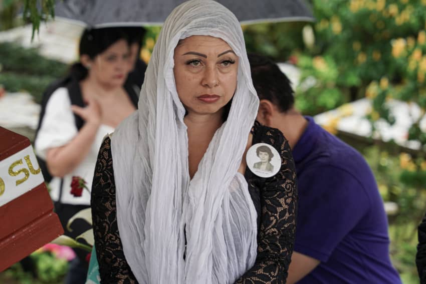 Mujer en Colombia con un pañuelo blanco y una fotografía prendida en el pecho recuerda a su familiar desaparecido en un acto de memoria por...