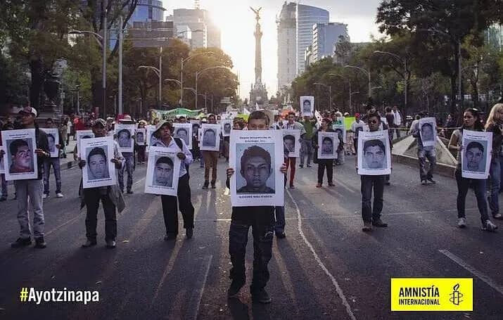 Personas marchan en Ciudad de México sosteniendo retratos de los 43 estudiantes desaparecidos de Ayotzinapa, en una protesta por verdad y justicia.