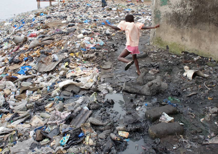 Niño caminando entre desechos y residuos tóxicos en un vertedero contaminado de Abiyán, Costa de Marfil.