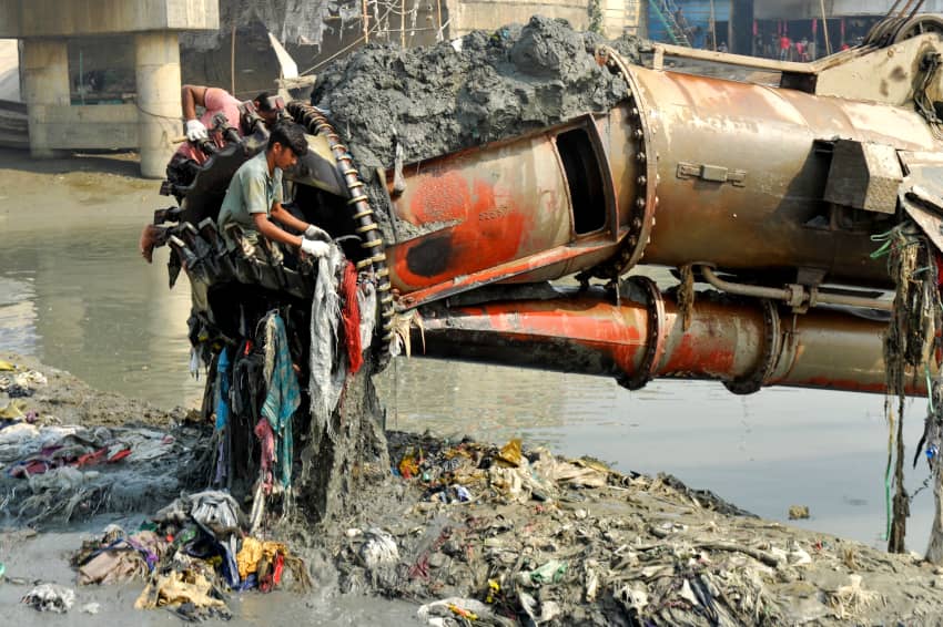 Personas limpian una máquina obstruida por plásticos y residuos en el contaminado río Karnaphuli, Bangladés.