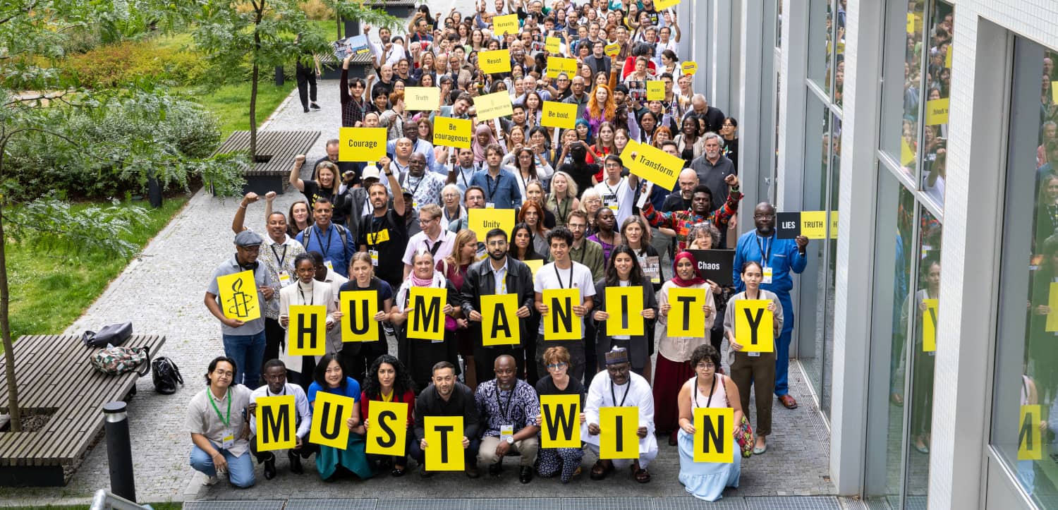Activistas de Amnistía Internacional sostienen pancartas a favor de la humanidad
