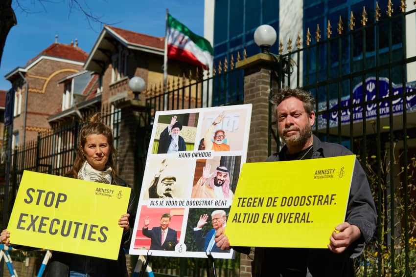 Activistas de Amnistía Internacional sostienen pancartas amarillas con mensajes contra la pena de muerte frente a la embajada de Irán, en una...