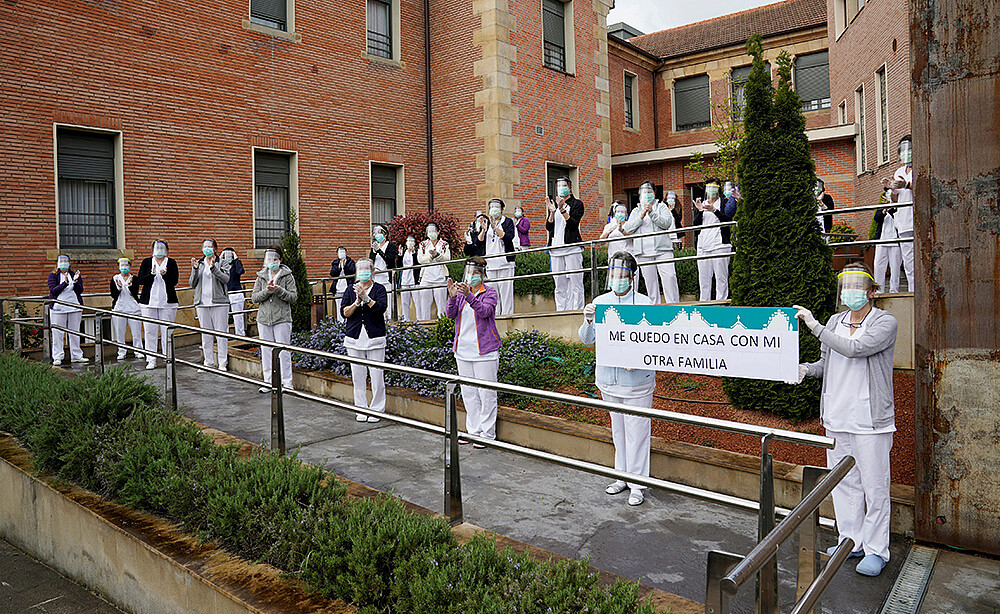 Trabajadores y trabajadoras de la residencia de ancianos Juan Calzada muestran una pancarta en la que se lee "Nos quedamos en casa con nuestra otra...