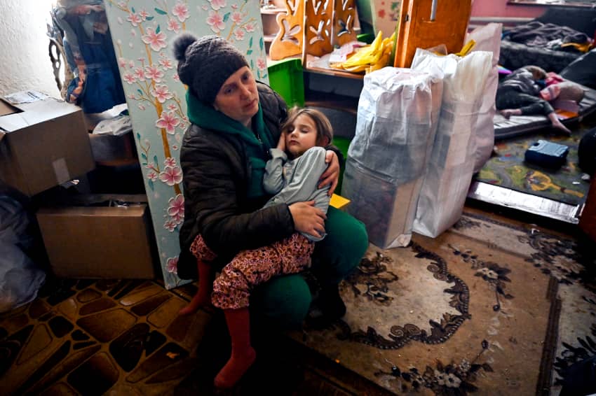 Una madre sostiene en brazos a una niña dormida