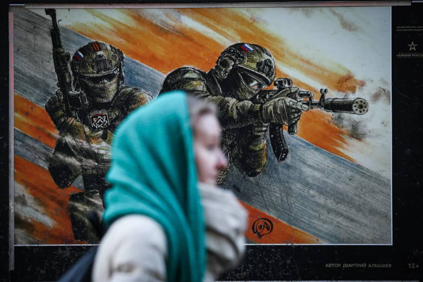 Una mujer pasa junto a un cartel con militares rusos en una exposición dedicada a la operación militar especial en Ucrania en la calle de San...