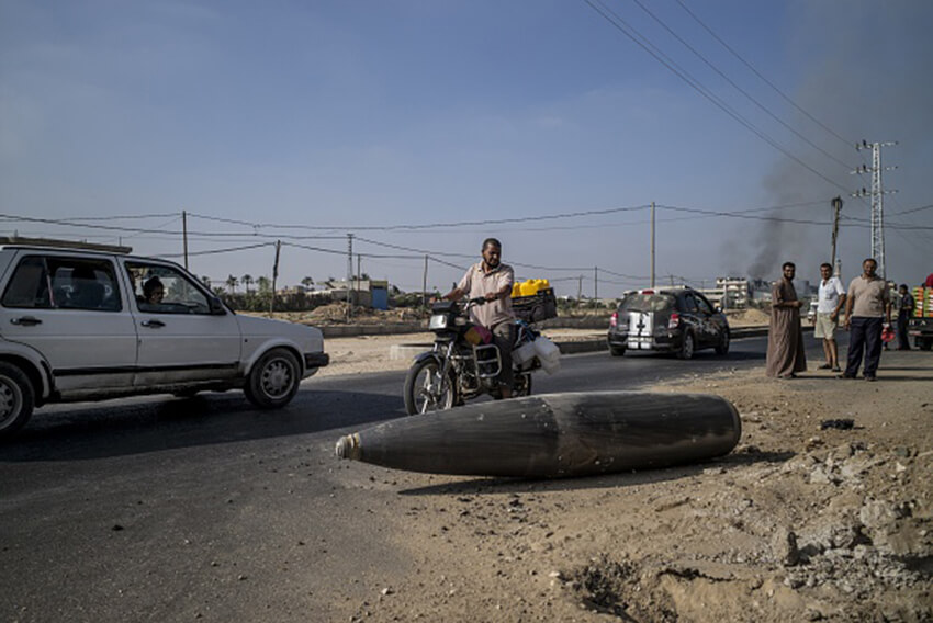Vehículos palestinos circulan ante un tanque de combustible externo de un avión de combate israelí en Deir al-Balah, en el centro de la Franja de Gaza, 1 de agosto de 2014