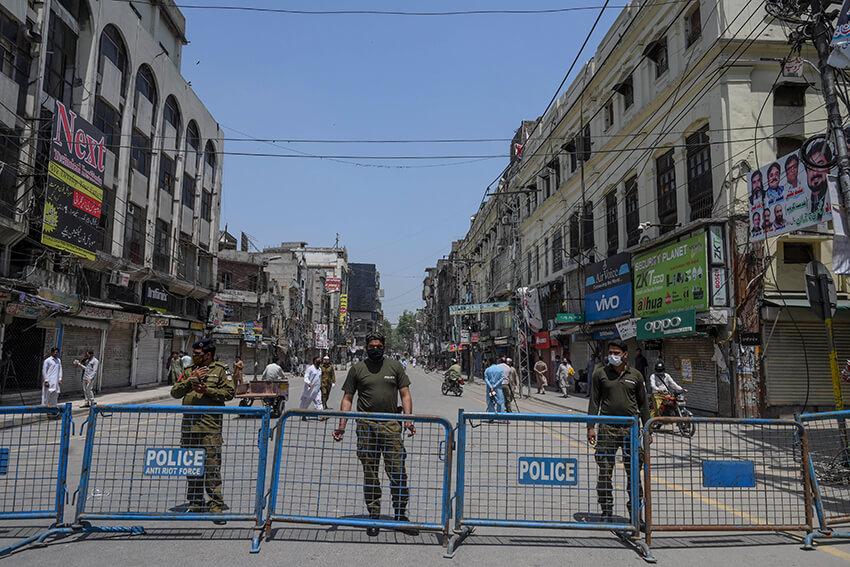El personal de seguridad monta guardia en una barricada cerca de un mercado después de que el gobierno aliviase el bloqueo nacional impuesto como medida preventiva contra la COVID-19, en Lahore, el 9 de mayo de 2020