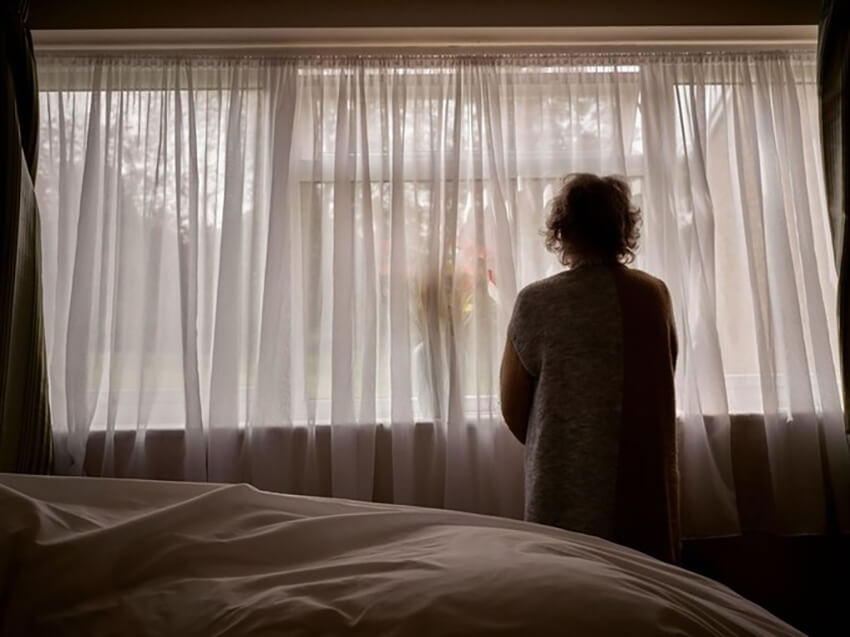 Una mujer mayor mira por una ventana durante la pandemia de Covid-19, Reino Unido, 16 de abril de 2020
