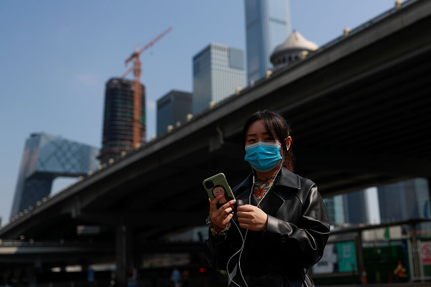 Una mujer usa su teléfono móvil en el centro de Beijing, China