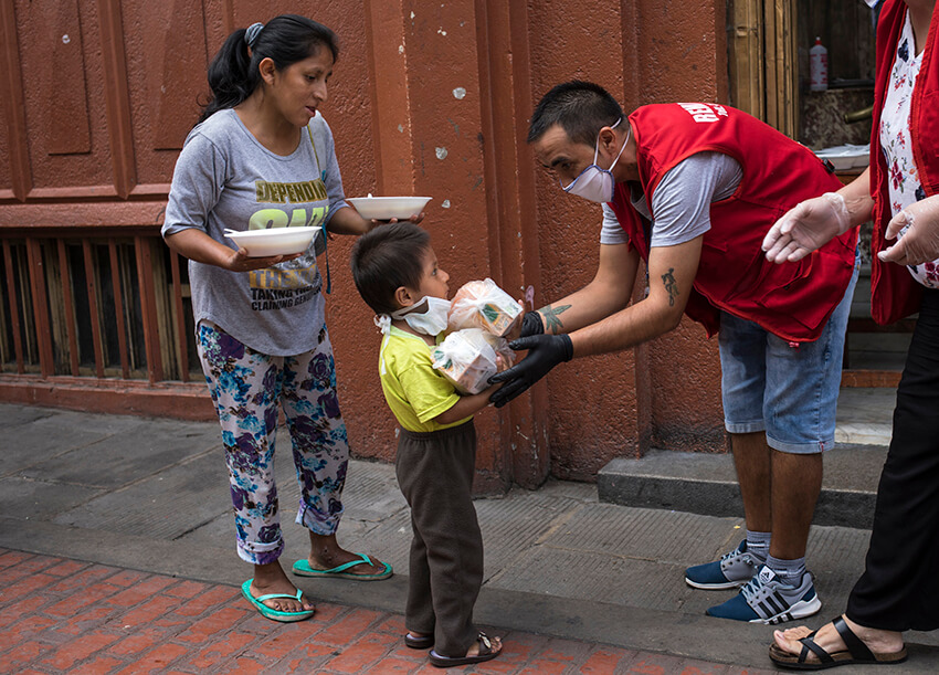 María Isabel Nieto y su hijo Jesús Anderson reciben su almuerzo, proporcionado a las personas sin hogar por una organización benéfica en Lima, Perú, el jueves 26 de marzo de 2020