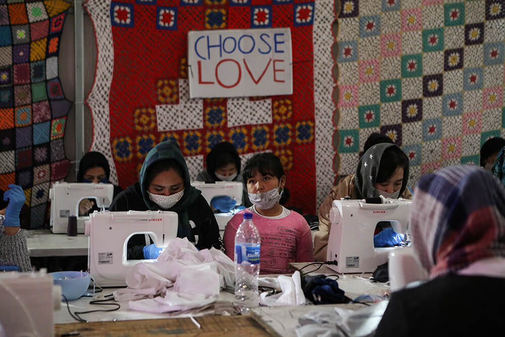 Migrantes del campamento de Moria cosen mascarillas faciales protectoras hechas a mano en las instalaciones de la ONG "Team Humanity"