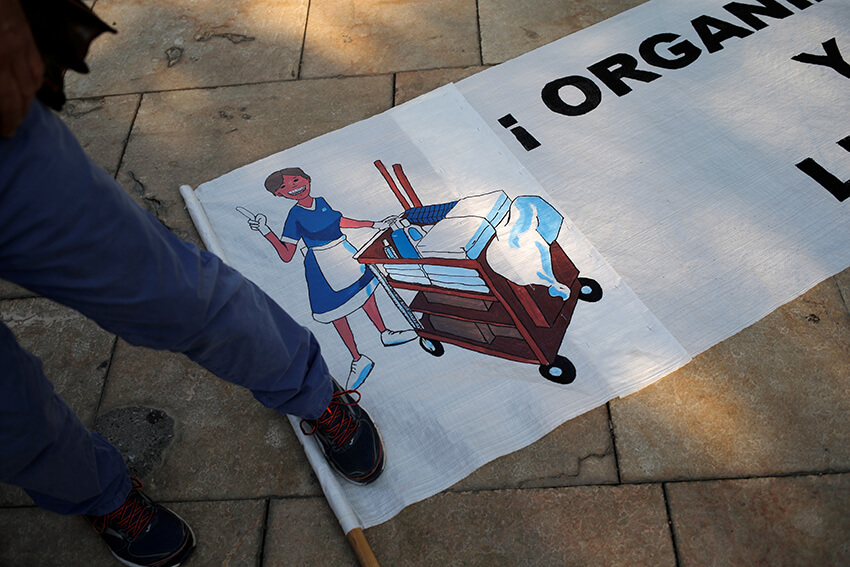Un hombre pisa una pancarta con el dibujo de una camarera conocida como Kelly, mientras las camareras protestan contra sus condiciones laborales