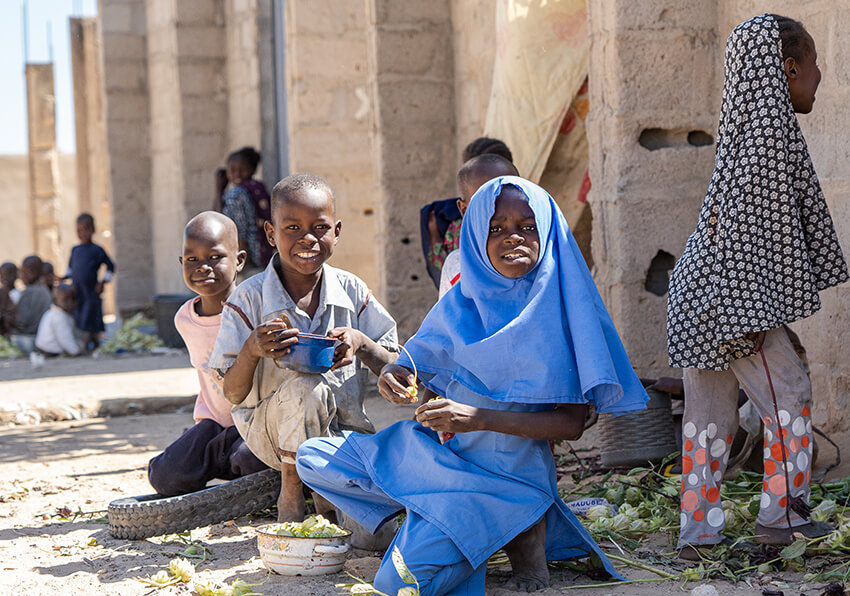 Después de terminar la clase de primaria, una niña (con uniforme azul) juega con otros niños que no están en la escuela, antes de volver a casa en Kaleri, Estado de Borno, Nigeria, 2019. 