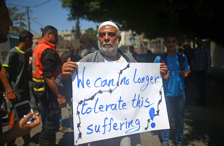 Un palestino cuya casa fue destruida por Israel sostiene una pancarta durante una protesta frente a la sede del Programa de las Naciones Unidas para el Desarrollo (PNUD), en la ciudad de Gaza el 20 de abril de 2016.