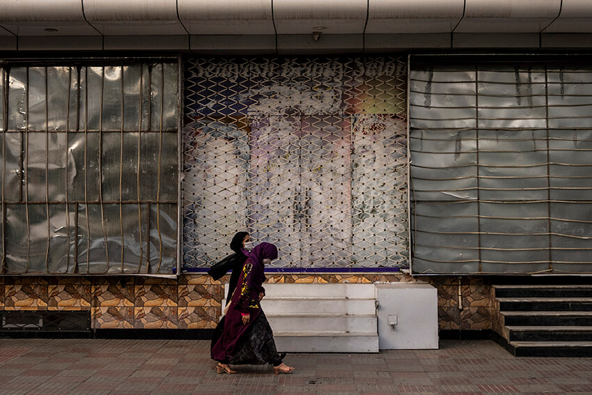 Unas mujeres afganas pasan por delante de un salón de belleza cerrado en Kabul, Afganistán, el 11 de septiembre de 2021. Desde que los talibanes se hicieron con el control de Kabul, se han eliminado o tapado varias imágenes en las que aparecen mujeres en el exterior de los salones de belleza. 