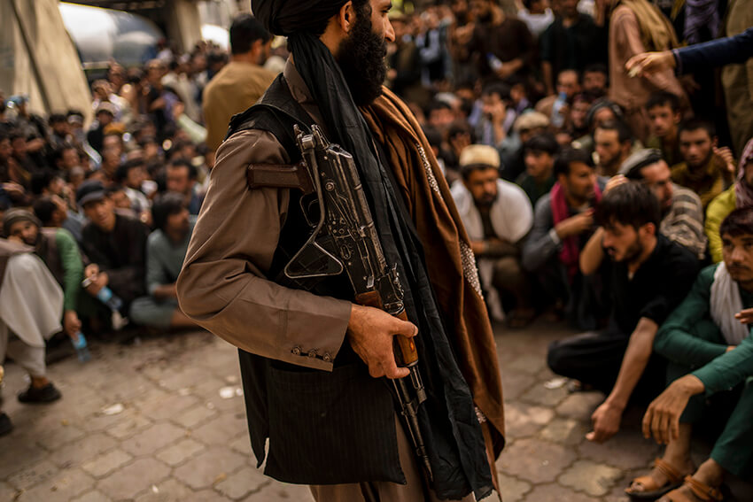 Un combatiente talibán controla a una multitud que espera para retirar dinero de una sucursal bancaria en Kabul, Afganistán, el 12 de septiembre de 2021.