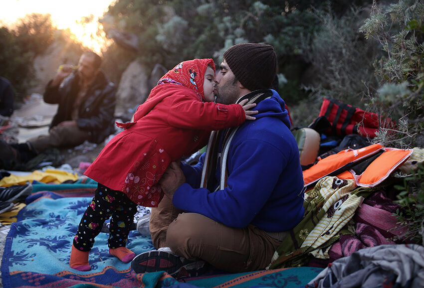 Un padre y una hija se dan un beso mientras esperan a viajar en un bote hasta las islas griegas desde Turquía