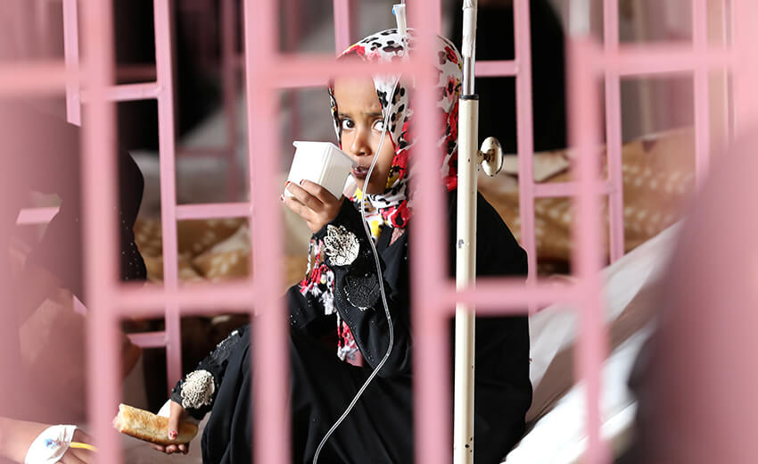 Una niña mira a través de las rejas desde su cama en el hospital al-Sabeen donde recibe tratamiento, Yemen