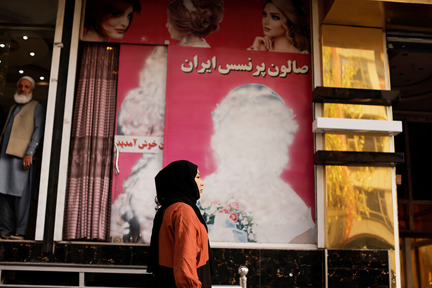 Una mujer pasa por delante de un salón de belleza donde las imágenes de las mujeres han sido desfiguradas