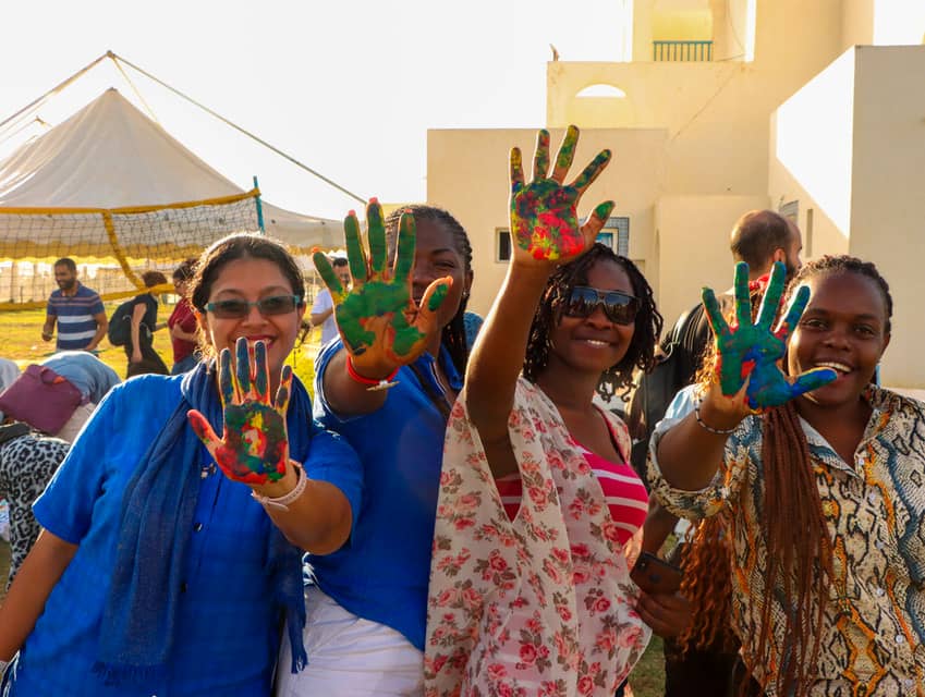 Cuatro mujeres mostrando la palma de la mano pintada con diferentes colores contra cualquier acto violento que una persona pueda sufrir