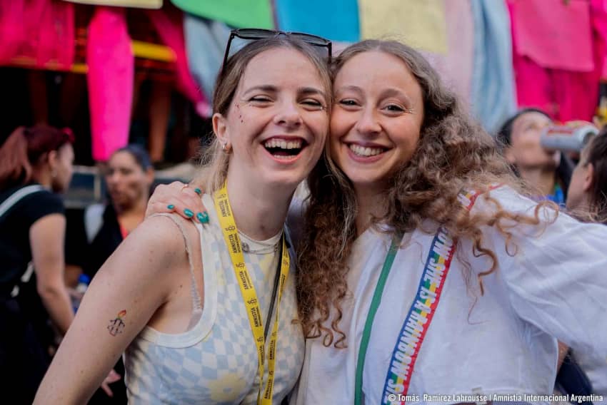Dos chicas se abrazan y sonrían mientras participan en una manifestación a favor de los derechos humanos y contra la violencia en todas y cada una de sus formas