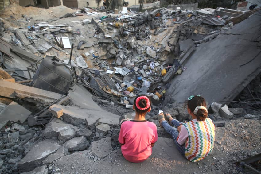 Unas niñas palestinas miran los escombros de un edificio dañado en la ciudad de Gaza